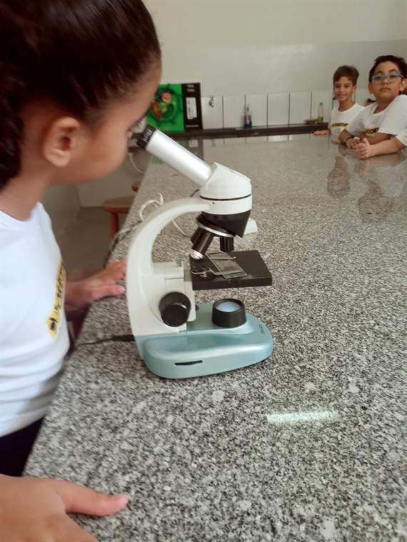 Aluna do Fundamental II usando o microscópio no laboratório de ciências do Castelo Objetivo