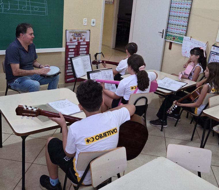 Alunos em aula de violão, com partituras nas estantes